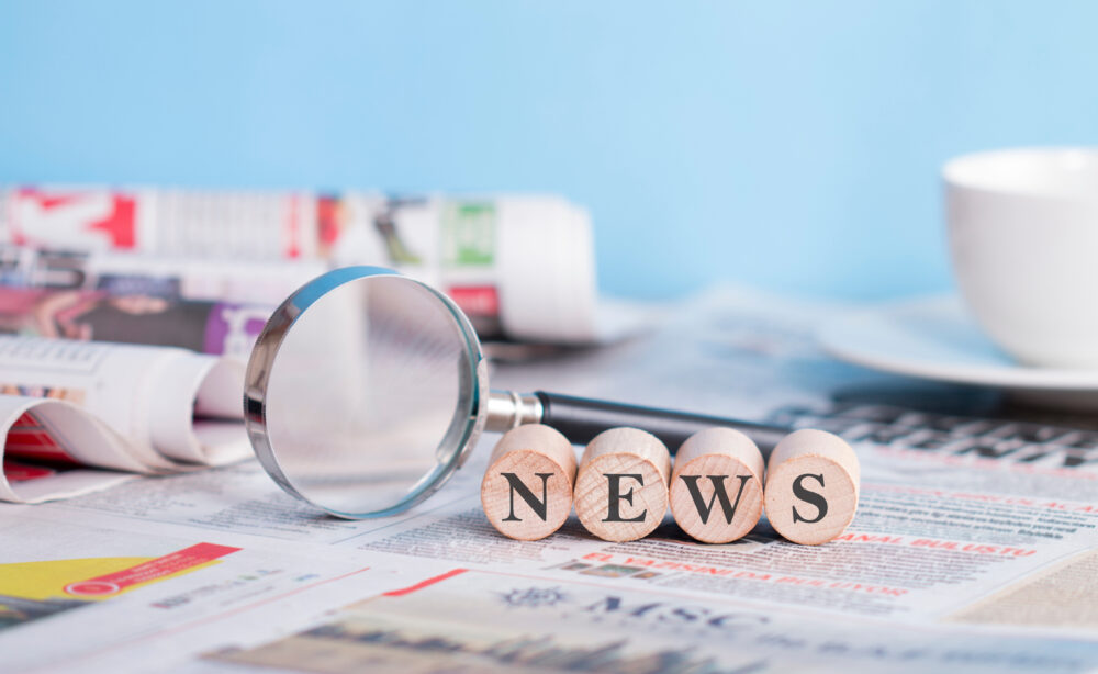 Newspaper and magnifying glass on the table, news wiritng on the cubes